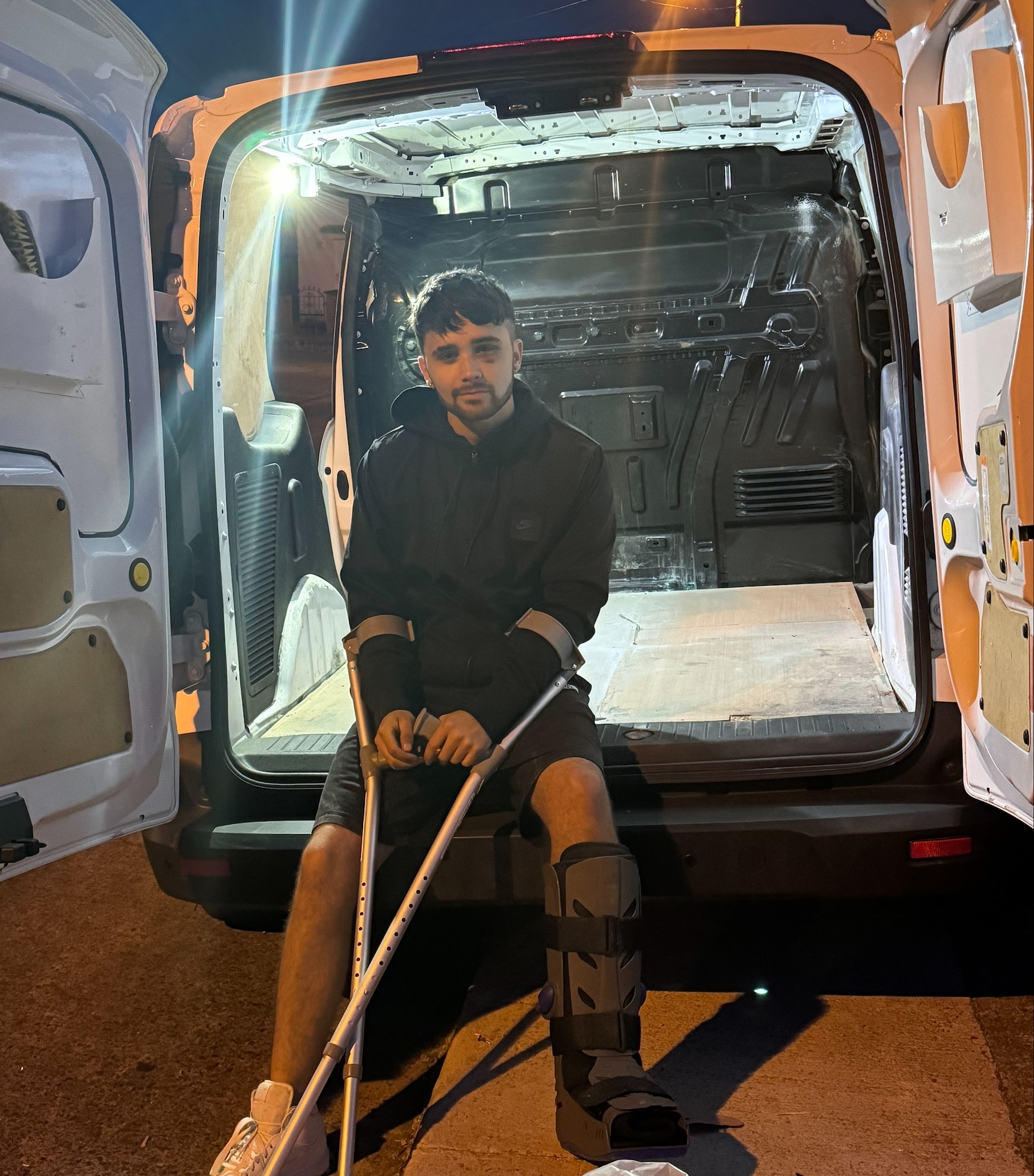 Mr. T sitting in work van on crutches — recovery and grit